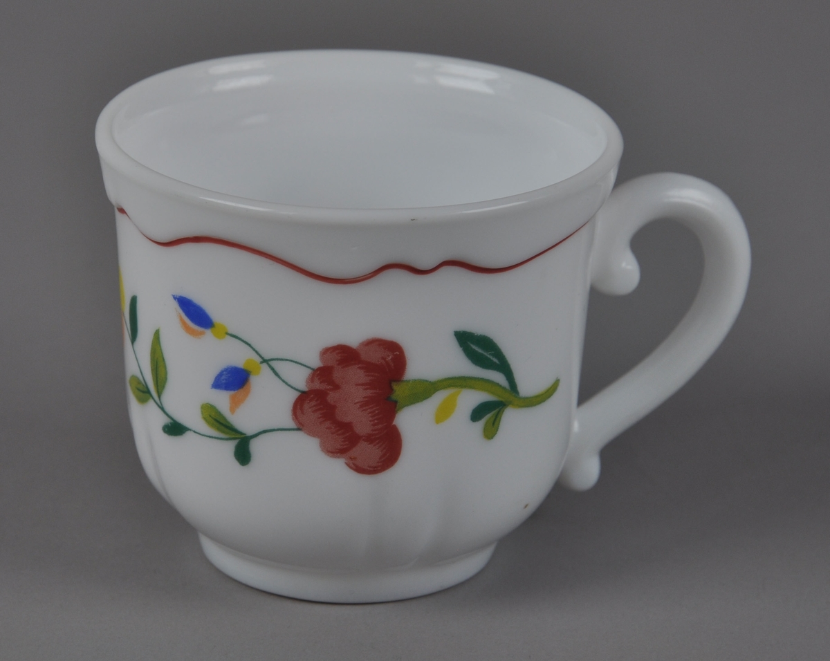 Kaffekopp av glassert keramikk, med hank. Koppen har malt dekor på utsiden med motiv av blomster og plantevekster, samt en bølgete rød stripe ved munningsranden.