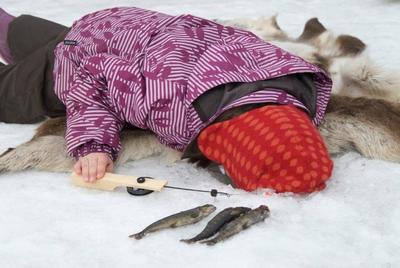 Jente som kikker ned i hull i isen på temdagen isfiske ved Anno Norsk Skogmuseum. Foto/Photo