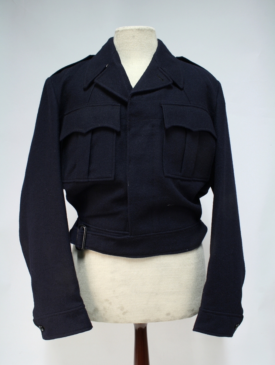 Mørkeblå gylfknappet jakke med innstramming i linningen.