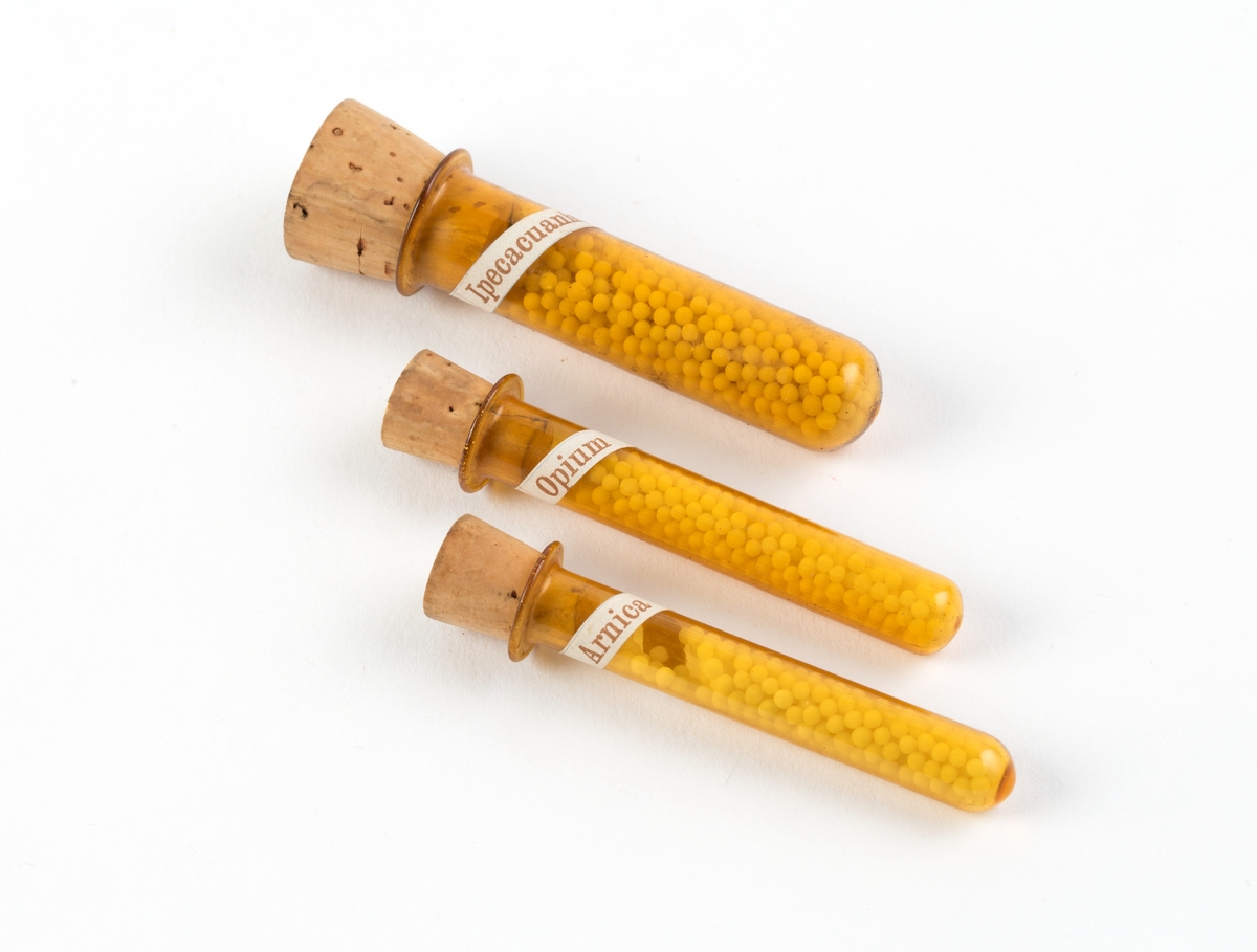 Skrin med hengslet lokk og innhold:
64 glassrør med kork påført nummer fra 1 til 64. Numrene korresponderer med plakat festet i lokket der virkestoffenes navn fremkommer. Påført nummer og navn også på hvert glassrør.