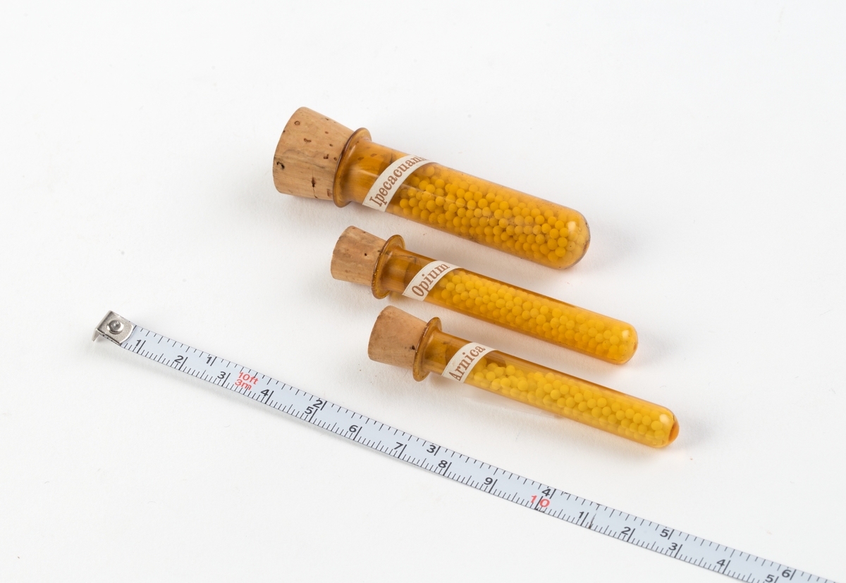 Skrin med hengslet lokk og innhold:
64 glassrør med kork påført nummer fra 1 til 64. Numrene korresponderer med plakat festet i lokket der virkestoffenes navn fremkommer. Påført nummer og navn også på hvert glassrør.