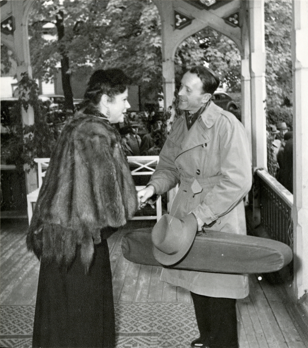 Victoria hilser på langeleikspilleren Olav Snortheim.
Bildet er tatt på verandaen utenfor Havestuen ved åpningen av Musikkhistorisk Museum.