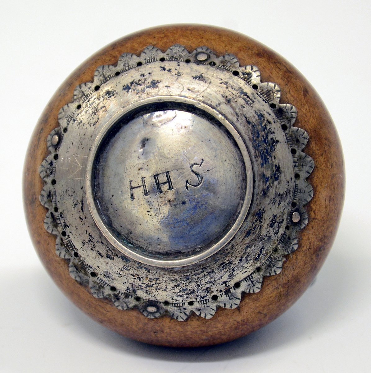 Fra protokollen: 1 snusflaske av træ med sølvbeslag, rund. Under bunden: H.H.S.
Gravert sølvbeslag på fot og topp, propp med lenke.