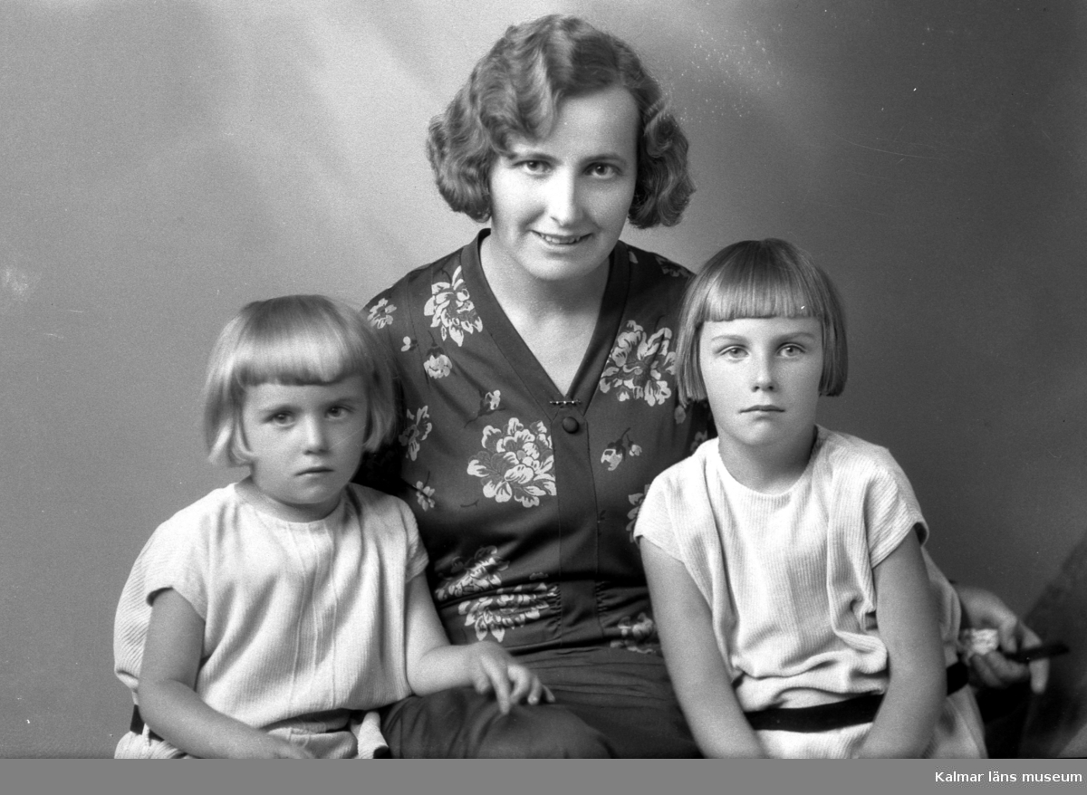 Ateljébild på en kvinna med två flickor. Enligt Walter Olsons journal är bilden beställd av fru Helga Gratte.