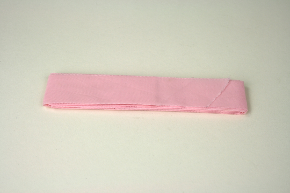 Band. Maskintillverkat rosa band, använt vid ett dop.