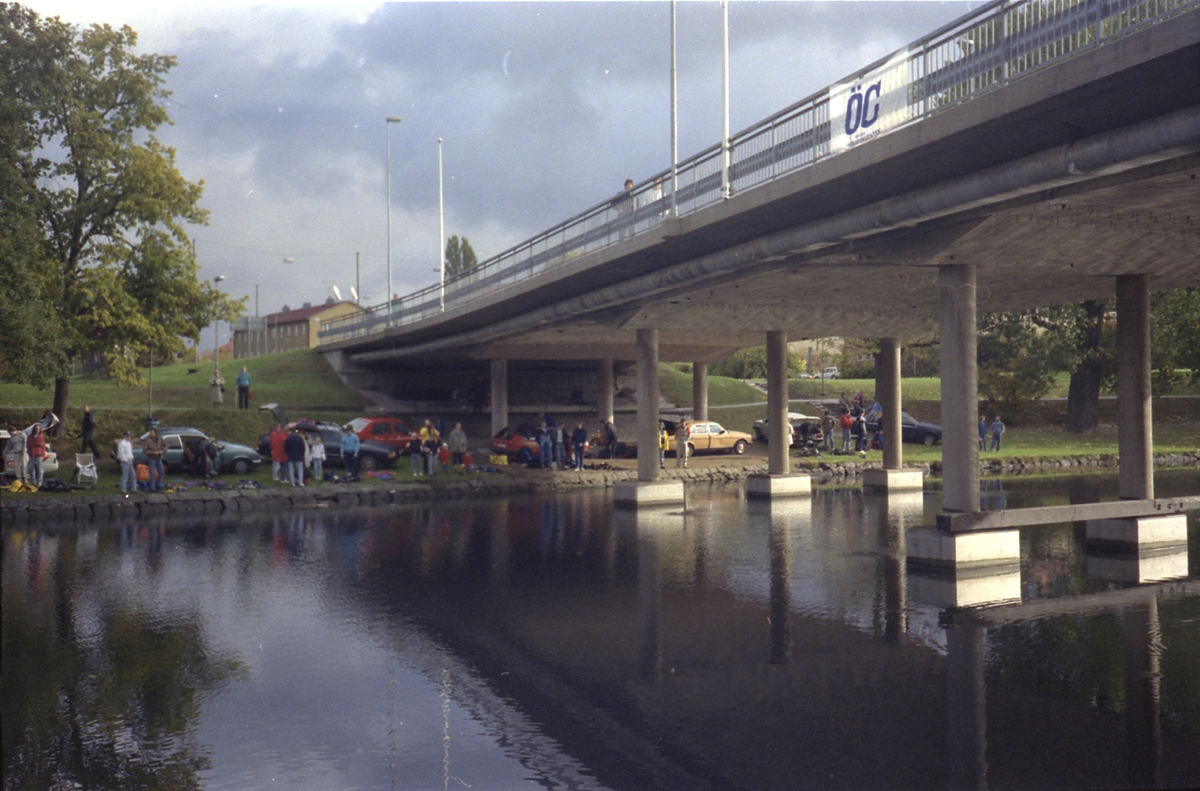 Orig. text: Dykartävling i Stångån. 1989-10-14.

Tävlingen äger rum kring Drottningbron både i nordlig och sydlig riktning, samt på bägge sidor av ån.
Drottningbron till höger i bild.
