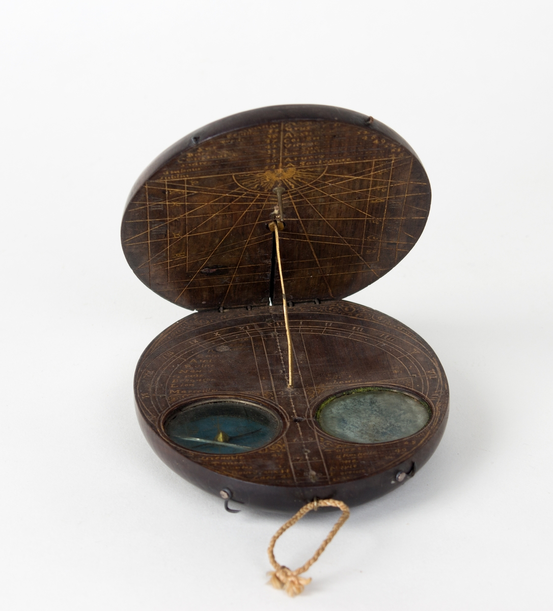 Instrument for måling av månefaser og solens hellning. Ovalt treobjekt som holdes oppe av en tynn messingpinne, sammelagt ligger to like store ovale treskiver oppå hverandre. På oversiden er det en klokkelignende rund måleskive (astrolabe?) i metall. Treskive to inneholder to kompassliknende skiver som er nedfelt i treverket.