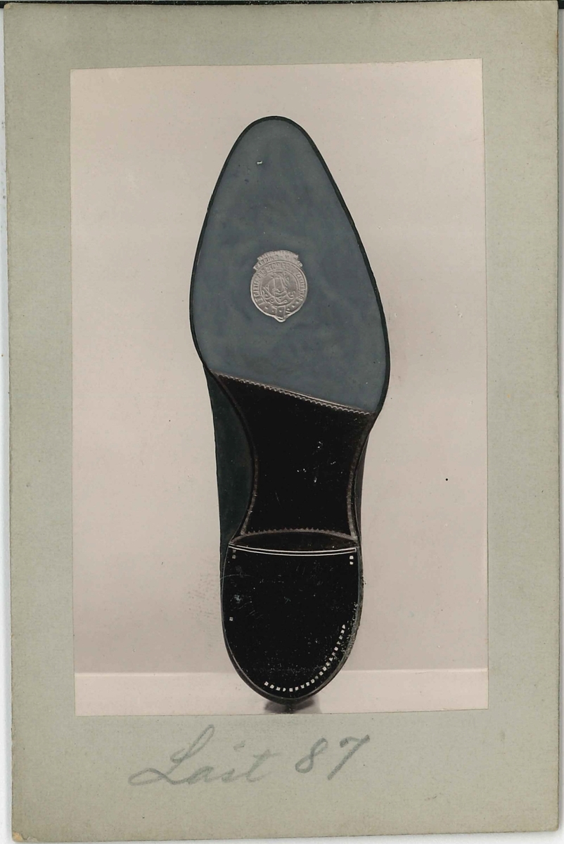Fotografi av ett skodon. Herrsko. Bild på undersidan av skon.

Använd som reklam på A F Carlssons skofabrik.

Ingår i en samling med 123 stycken kort i kartong.