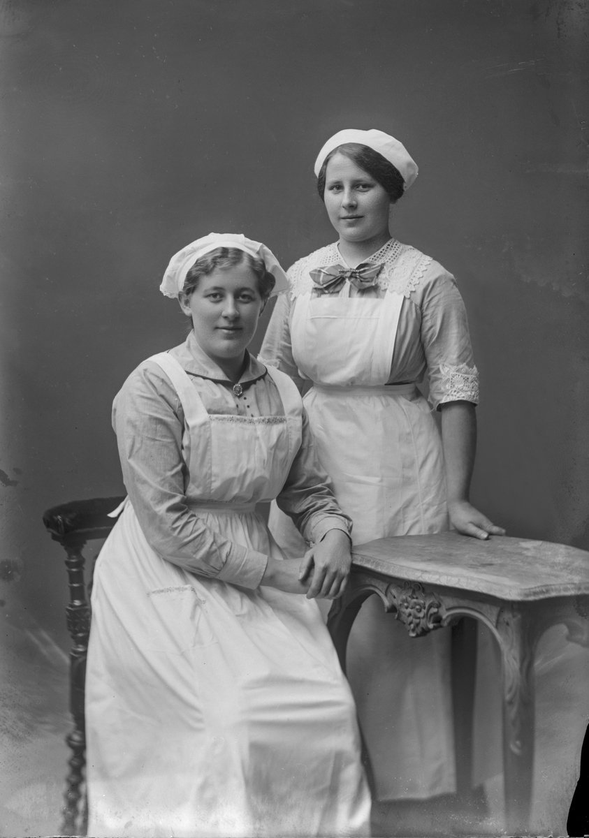 Porträtt från fotografen Maria Teschs ateljé i Linköping. 1915.04.08. Beställare: Ella Anderson. Två kvinnor i tjänsteklädsel.