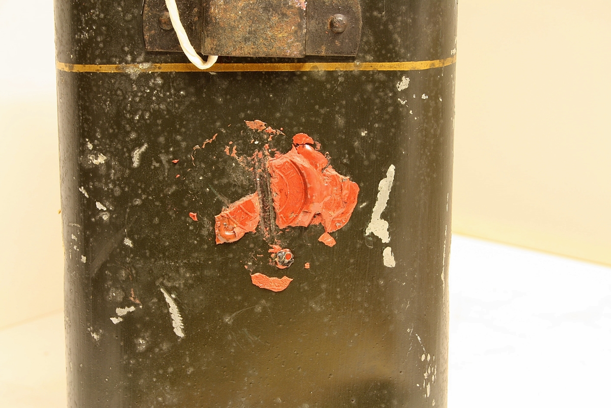 Avrundet, rektangulær boks. Den norske løve på fronten. Rester etter rødt segl. Hvit snor i plast.