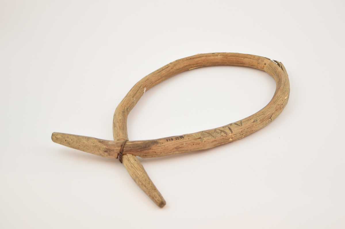 Laget av en hel gren av einer, bøyd i dråpeform og festet ved et utskåret hakk i begge endene med ombundet ståltråd. Initialer skåret inn i gjenstanden.