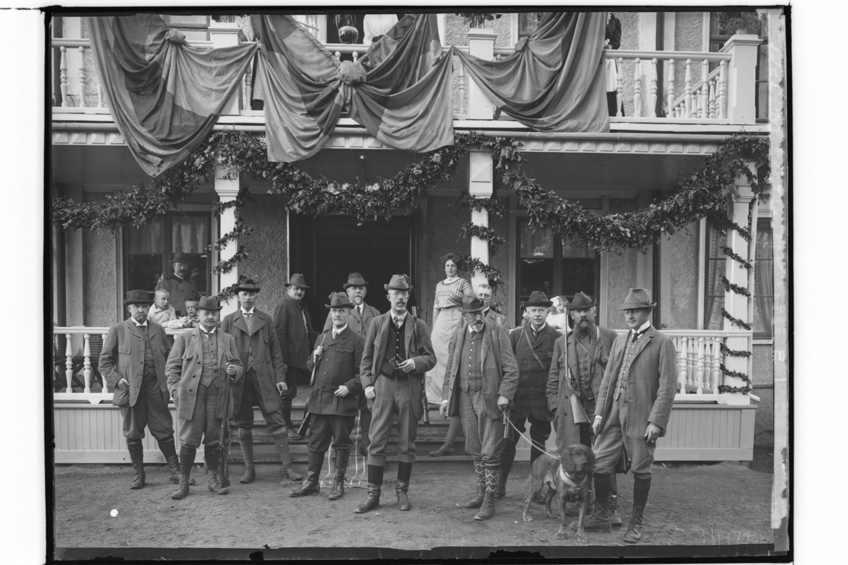 Kungligt jaktsällskap, Haddebo.
Kung Gustaf V, jägare, 11 män, en älghund.
Barn och kvinna på verandan.