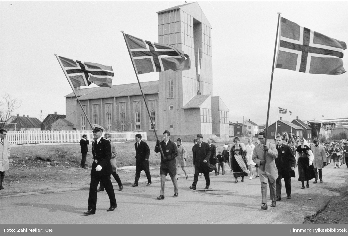 Vadsø, 17.mai 1970. Korpset spiller i gatene. Vadsø kirke i bakgrunnen.