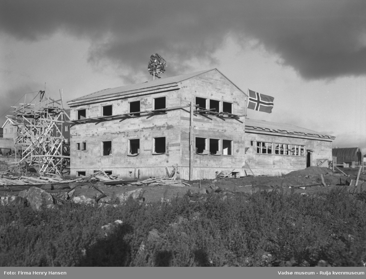 Vårbrudd 1949.  Bildet viser Vårbrudd under oppføring. Bygningen har nå "tett tak" og vi ser kransen som er heist på mønet og flagget vaier. Forskalinger og bygningsmaterialer ses rundt bygningen. I høyre billedkant skimtes en nissenbrakke.