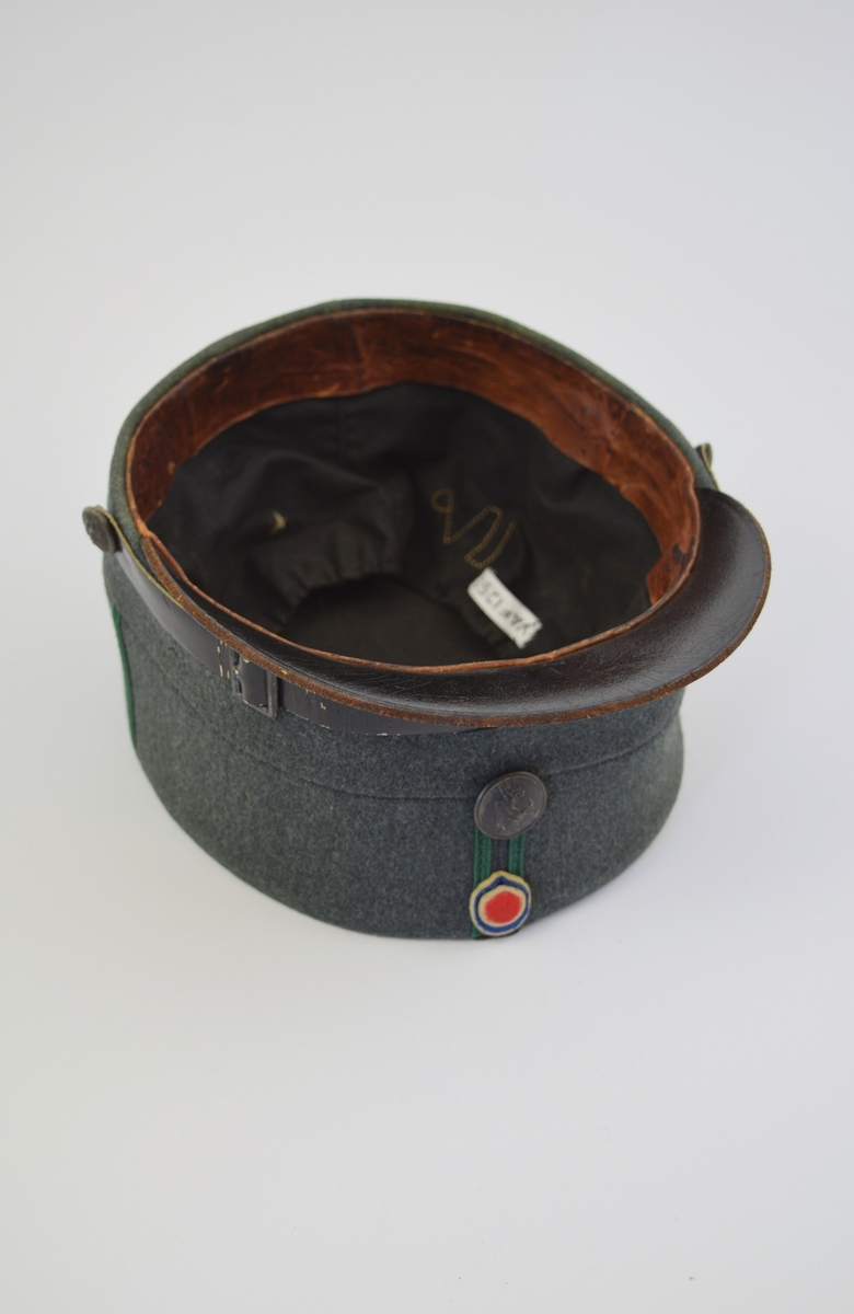 Uniform i tre deler: jakke, lue og patronveske. Innsvinget jakke med fire lommer,enkelt spent,nedbrettet krage. Bøtteformet lue med distinksjoner. Svart lærbrem og svart lærrem som går over bremmen. Kvadratisk patronveske i grønt lerretsstoff, med stor svar trykknapp foran.