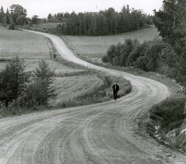En person vandrar längs en kurvig väg i Garluö, Hälsingland.