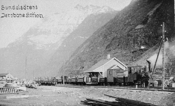 Sunndalsøra jernbanestasjon. Et svært sjeldent bilde fra en stasjon som var operativ bare mellom 1916 og 1919. Toget trekkes av damplokomotiv nr. 1 "Litjmaskina". Vogn nr to etter loket er en av banens kassevogner ombygd til passasjervogn.