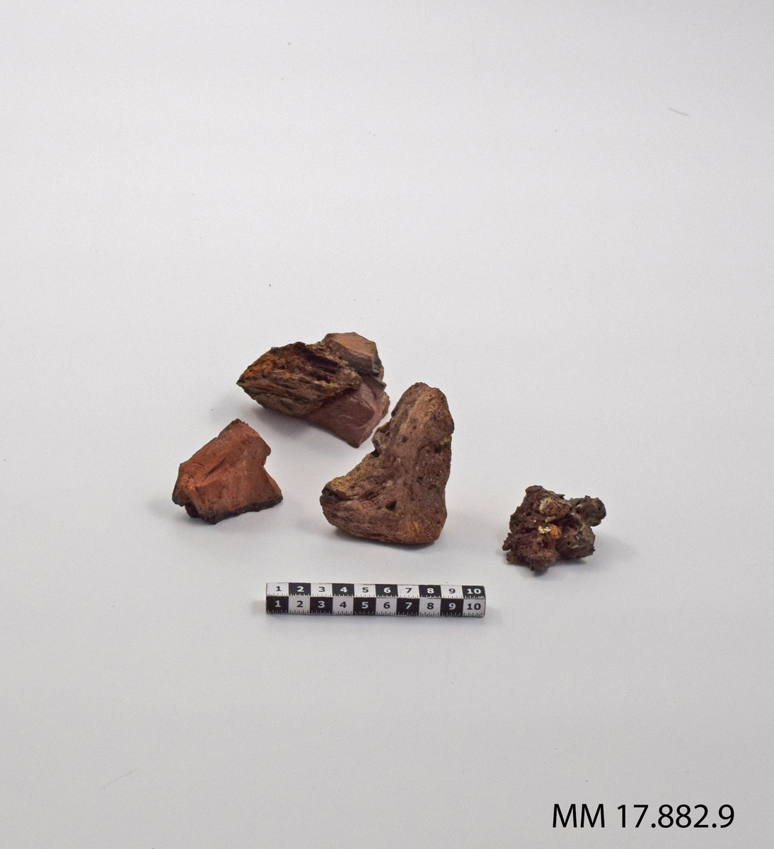 Sjöfynd från vraket Nya Riga. Tegel, femton stycken mindre fragment, vissa tillsammans med järn och trä.