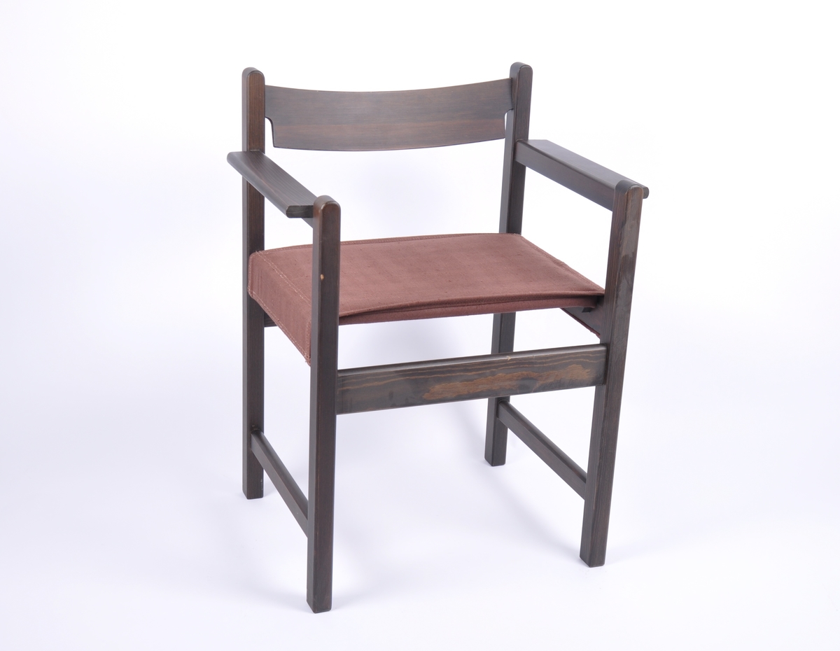 Enkel, rett stol med armlener. Overflate i mørk beis. Seteplate er trukket med polstret grovvevd mørk brunt stoff.