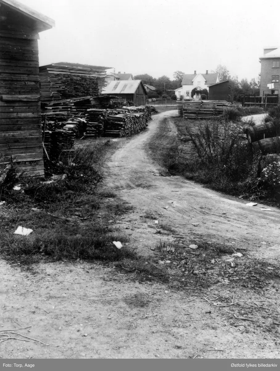 Mysen i Eidsberg. Sagtomta fra ca. 1955, våninghuset i midten "Degnes-villaen". Plankestabler til Hamil-saga. Bygning til høyre: Dagfinn Mysens kolonialforretning. Isbinge under klesvaska!