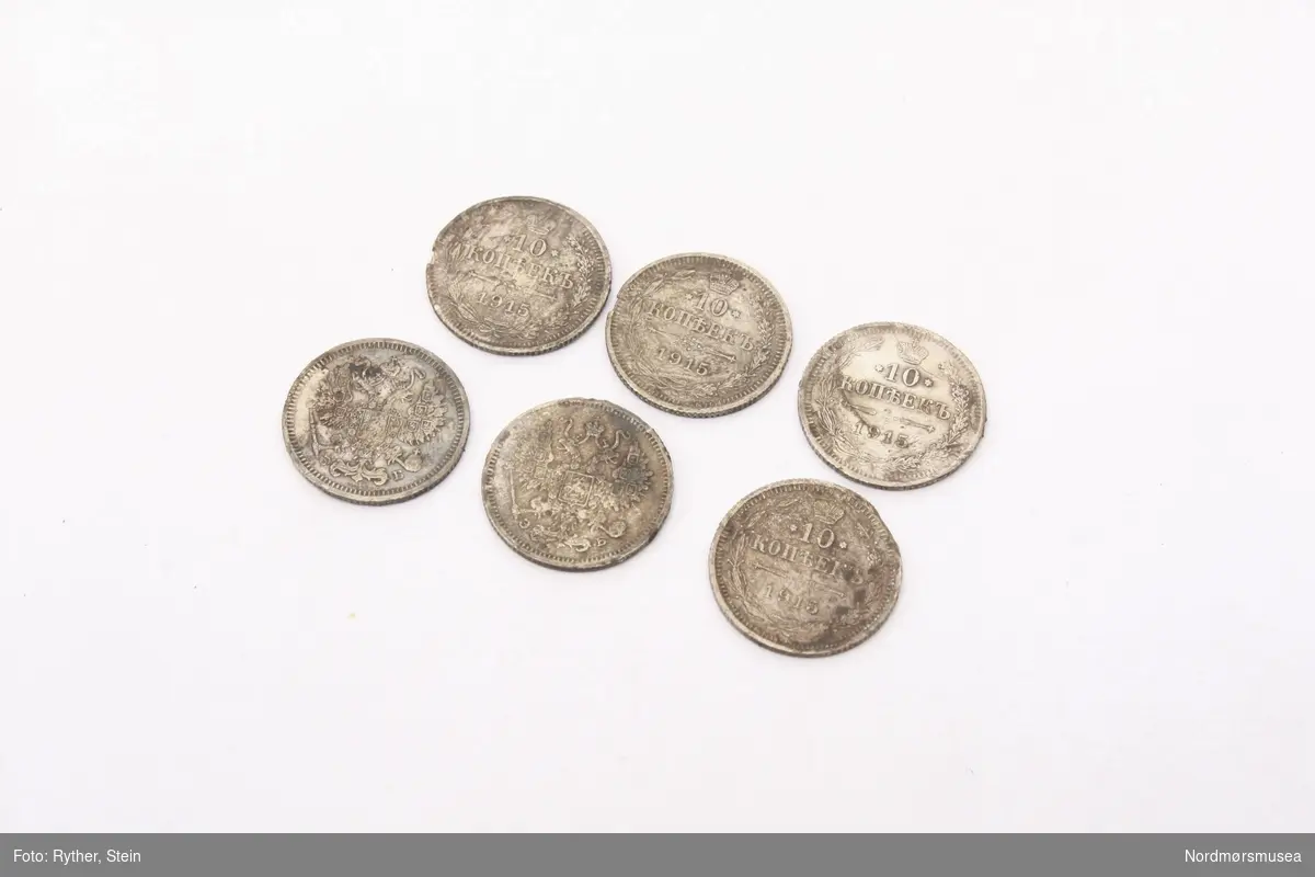 Forskjellig håndarbeid samlet i en eske som består av russiske mynter, omgjort til redskap og smykker. Esken består av 6 små mynter, 3 små mynter med anheng, 4 større mynter banket til en skålform, en skjei laget av en større mynt fra 1841 med skaft fra en opprinnelig skjei. Og en stift og to stenger i jern.

Alle myntene er russiske, og alle myntene er i metall.