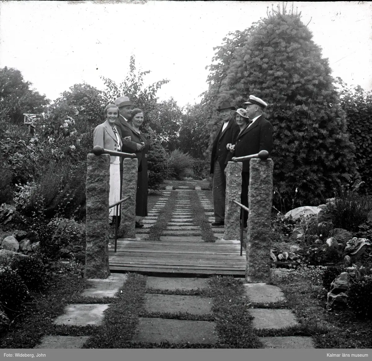 Några personer på en bro i Widebergska trädgården.