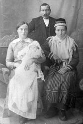 Studioportrett av to kvinner og en mann med et dåpsbarn.