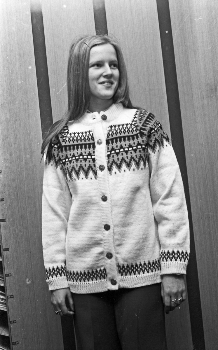 Ung kvinne som viser fram strikkegenser.