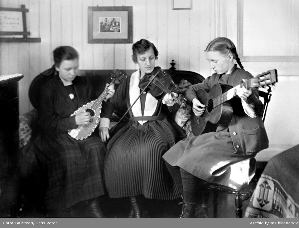 Musisering i stua på Hollenderbjerget i Moss ca. 
.1922-1925. Fotografens døtre, søstrene Lauritzen, musiserer i stuen sammen med sin kusine, Rakel. 
Fra venstre: Ingertha, Rakel og Solveig.
De spiller henholdsdvis; mandolin, fiolin og gitar.