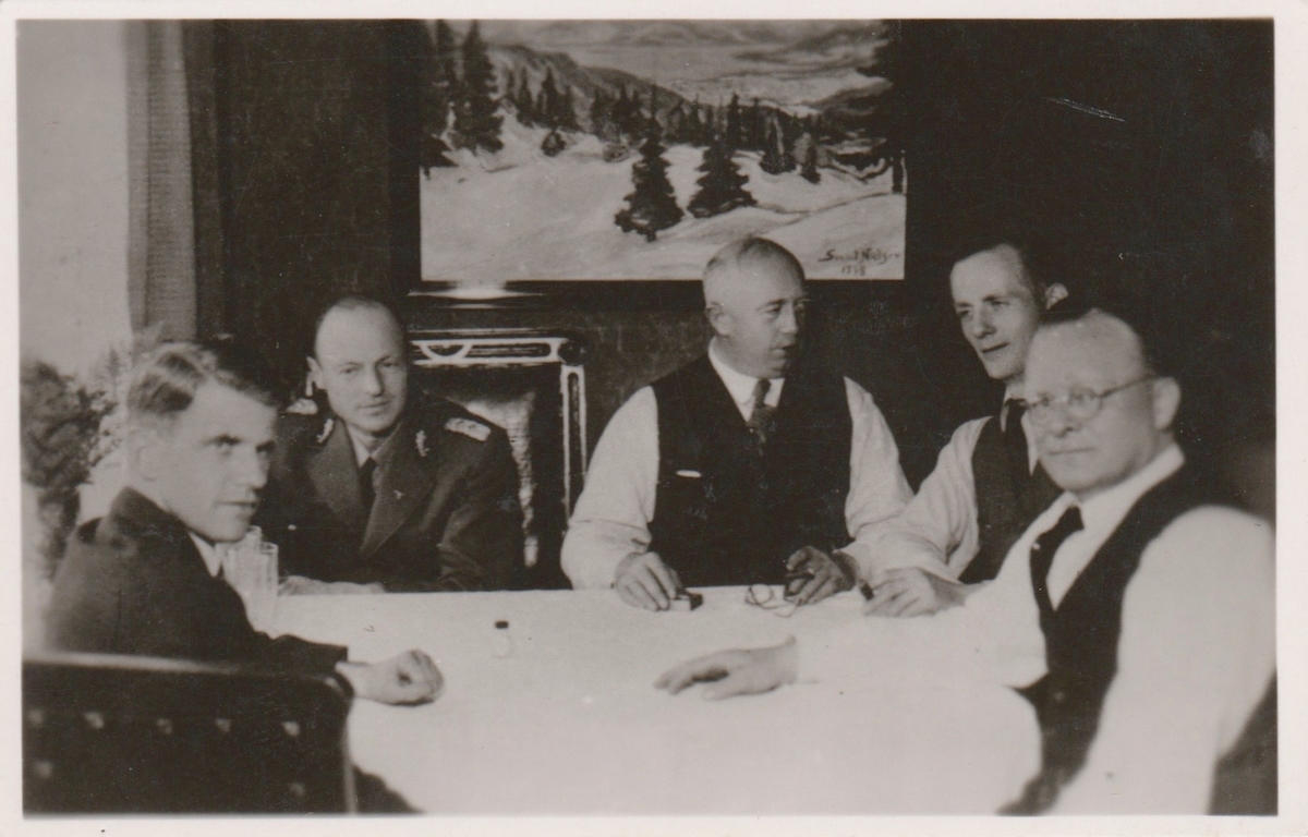 Fem menn sittende rundt et bord. En av dem bærer norsk politiuniform modell 1942.