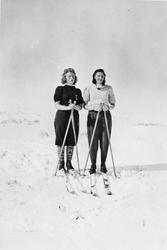 Personer, klær, ski og skistaver.