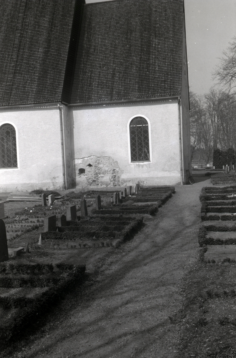 På bilden som visar Mortorps kyrka ser man igenmurade nischer och dörröppning i korets södra vägg. I förgrunden en kyrkogård.
