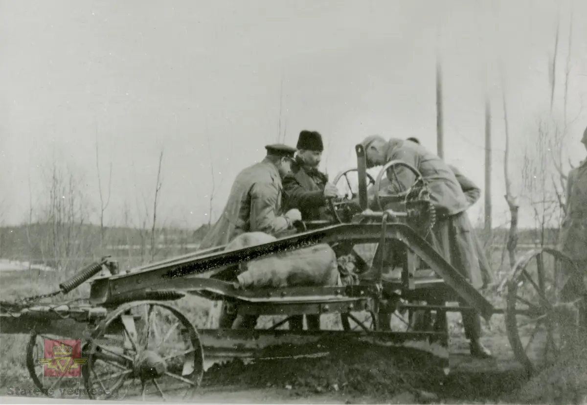 Amerikansk veghøvel "Russel Grader"  i arbeid i Østfold 1924, i følge merking.  Ref. til "Meddelelser fra Veidirektøren", Nr. 47-mai 1924. Artikkel om "Prøve med den amerikanske veihøvel "Russel Grader" samt skrapning av veibanen med "Western" skrape", av overingeniør Thor Olsen. Befaring  med vegdirektoratets og Østfold fylkets ingeniører.  Andre bilder av veghøvelen som er illustrert i artikkelen vises i bildeframvisning 2/5 og 3/5. Bildeframvisning 4/5: "Skraperne av "Western"-typen forarbeides som nævnt ved fylkets verksted og utstyres nu med en fast arm paa den ene side for styring av hele redskapen foruten den bevægelige for stillingen av bladene , som det vil sees av fig. 5". Bildeframvisning 5/5: Vedlikeholdsarbeid med amerikansk vegskrape utføres i Østfold.