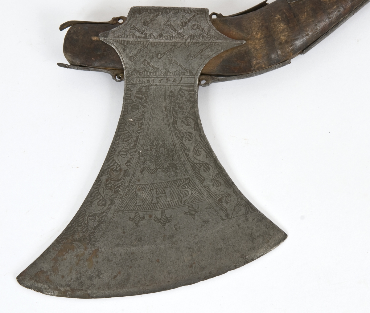 Asymmetrisk blad med lang øvre spiss og kortere nedre spiss. Bladet er klieformet. med påsmidd egg- Øksen har stset dekor på begge sider. Øksen er merket med IHS på begge sider  Skjellmønstet smedmerke på utsiden. Innskipsjon på utsiden NILS. G VIKRANDSØN  På innsiden ANNO 1634
Øksehammeren har skaftehull og skinner.
Gammelt skaft med jernskinner og rester/ av / merker etter bånd..Skaftet har doppsko med pigg og fire fliker med ringer på enden.
Skaftet er krummet.