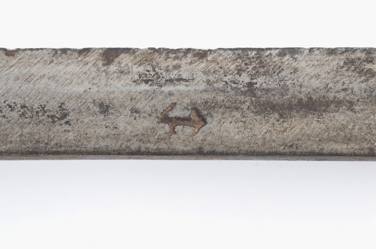 Kjegleformet 6 kantet knapp med nitteknapp og smidd bladdekor. Tregrep Øvre del av festet msgnler. Rette parerstenger med rombeformede avslutninger.
Rett tveegget klinge med kileformet  tverrsnitt og ryggslipning mot spissen