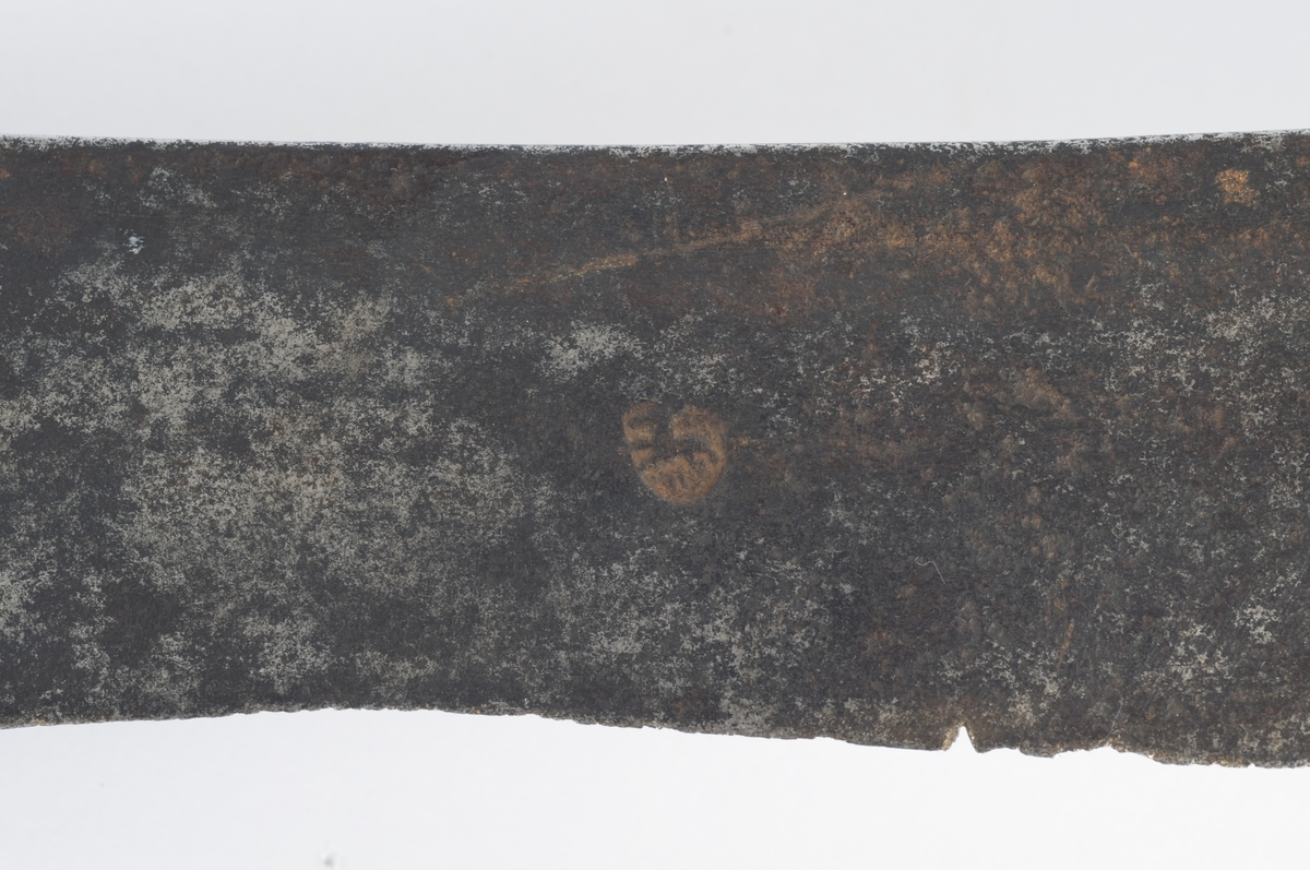 Pyramideformet  knapp med punslet strekdekor. Tregrep. Runde parerstenger med filt strekdekor og svakt nedbøyd bakre parestang. Fremre parerstang er brukket. Kurvfeste med runde bøyler med utsmidde, skråfilte midtpartier. Nyreformet parerplate med tombøyle på innsiden. 
2 sidebøyler på innsiden.
Enegget, kileformet krum klinge med  ryggstilt blodrand. Gjeddenebb.  
Klingens innside merket med ett smedstempel.