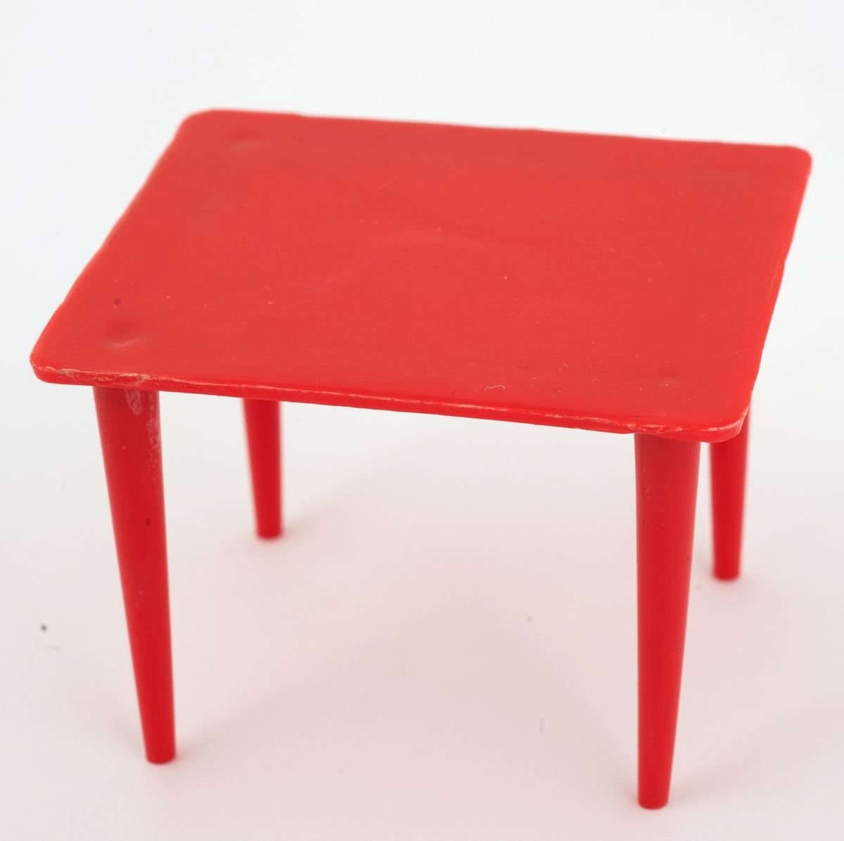 Spisebord i rød plast til dukkehus.