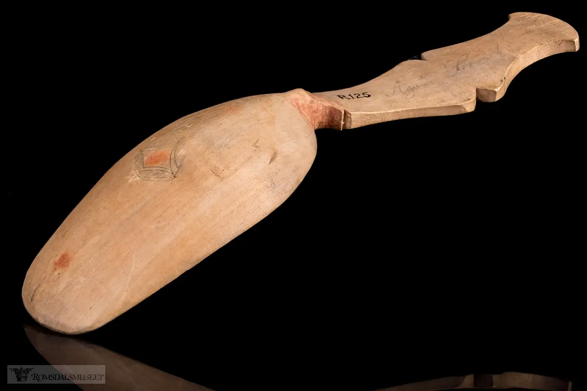 Stiliserte blad som er risset inn og fargesatt med mørk blå farge. Detaljer i rødt.