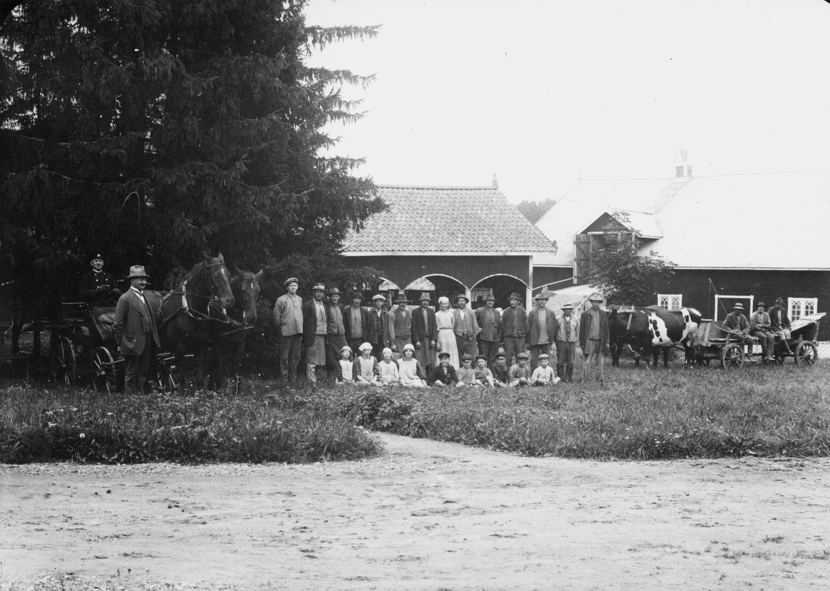 Arbetsstyrkan vid Valla gård omkring 1922. Till vänster gårdens inspektor Emil Karlsson. Bakom denne kusken Oskar Gustafsson med hästarna Walf och Sally. För övriga personnamn hänvisas till orginalbilden. I bakgrunden gårdens vagnsskjul och ladugård.