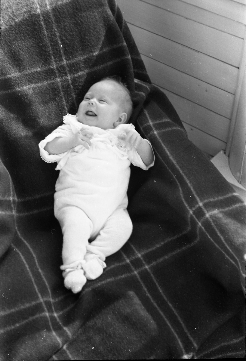 Uidentifisert lite barn. Serie på 10 Bilder. På noen av bildene holdes barnet av kvinner som bare delvis vises, og som heller ikke er identifisert.