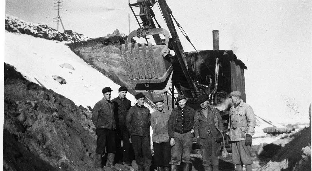 Ein av dei første gravemaskinane frå Brødr. Søyland as er i sving med jernbanetraseen. Lengst til høgre står Bjarne Wiig og til venstre for han Kristian Søyland, den eine av "brødrene".