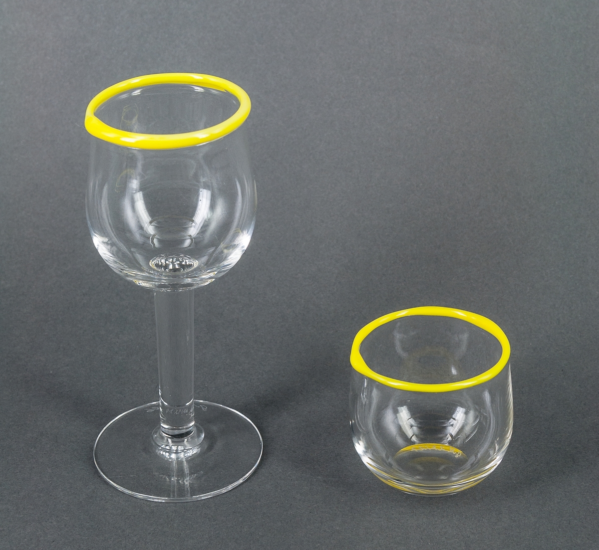 Sherryglas i halvkristall. Servisglas. Sandviks glasbruk, design Gunnar Cyrén. Mjukt konvext utan fot. Drivet, med gul pålagd kant.
