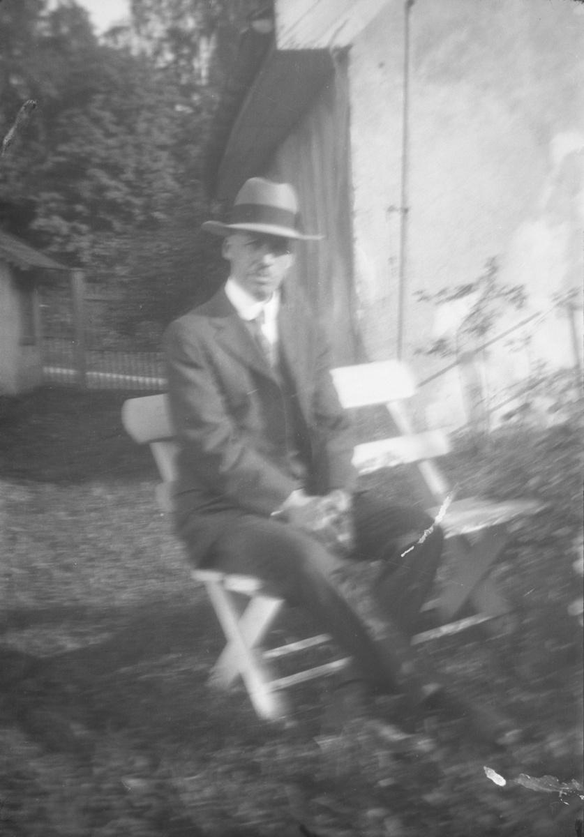 Mann på stol i hage.