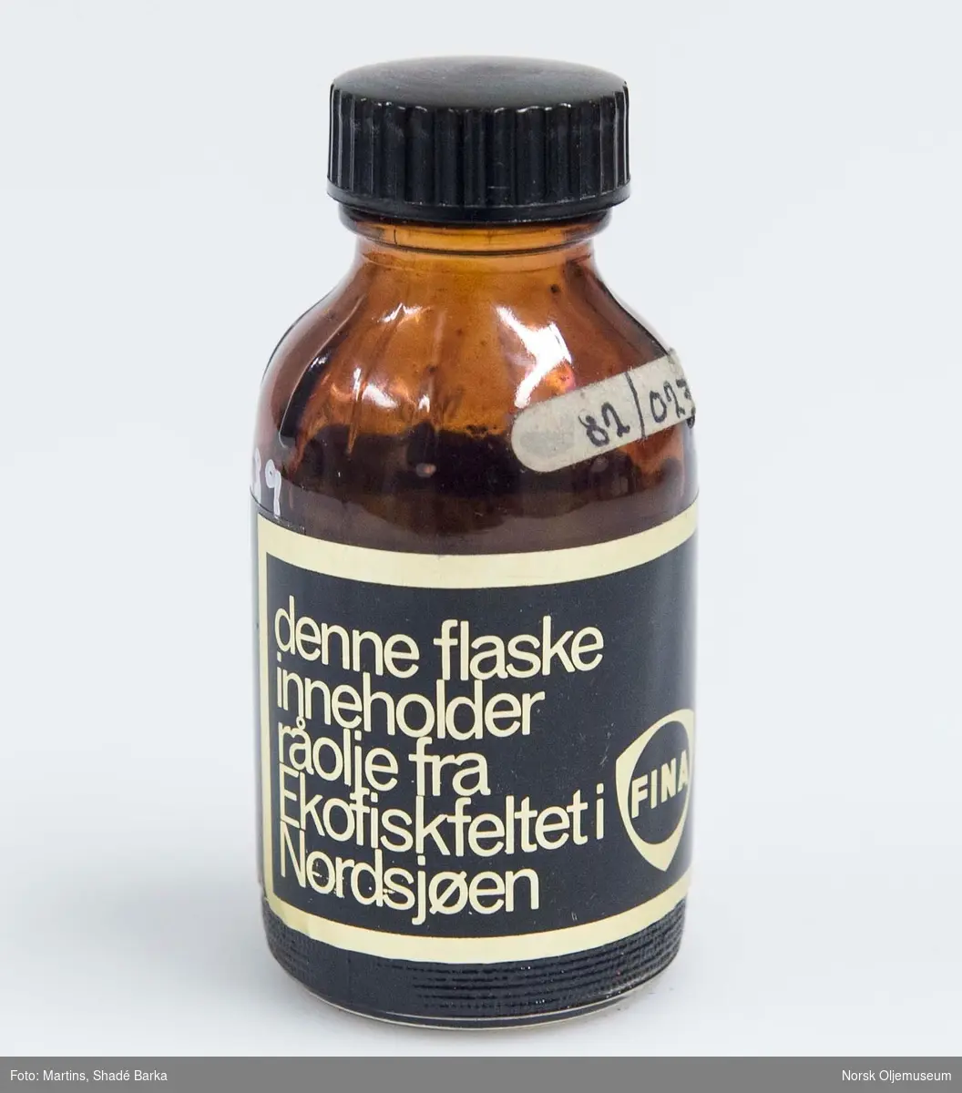 Oljeprøve i glassflaske med plastkork. Oljeprøven er fra feltet Ekofisk, med oljeselskapet Finas logo for Ekofisk.