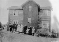 Familie oppstilt foran bolighus. På Nedre Sveen. 
(Navn - s