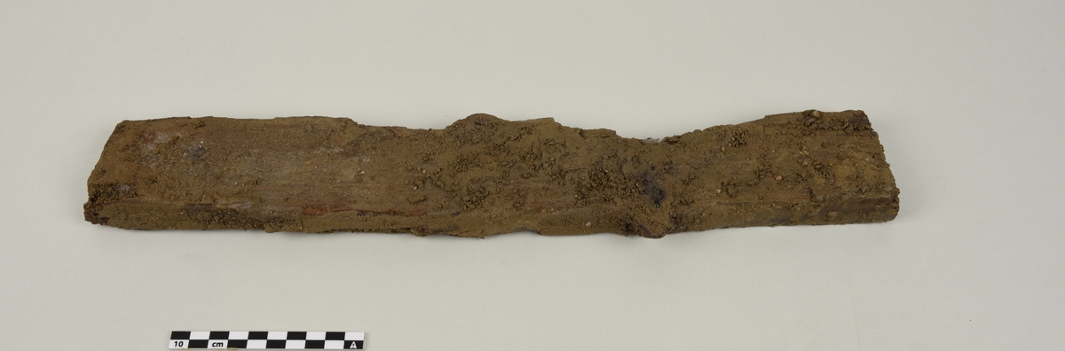 Deler av en rektangulær gravkiste.
Det er 4 avlange rektangulære treplanker og tverrplanker fra kisten. Hver er laget av ett stykke tre. Det er rester etter spiker og misfarging på grunnen av rust.