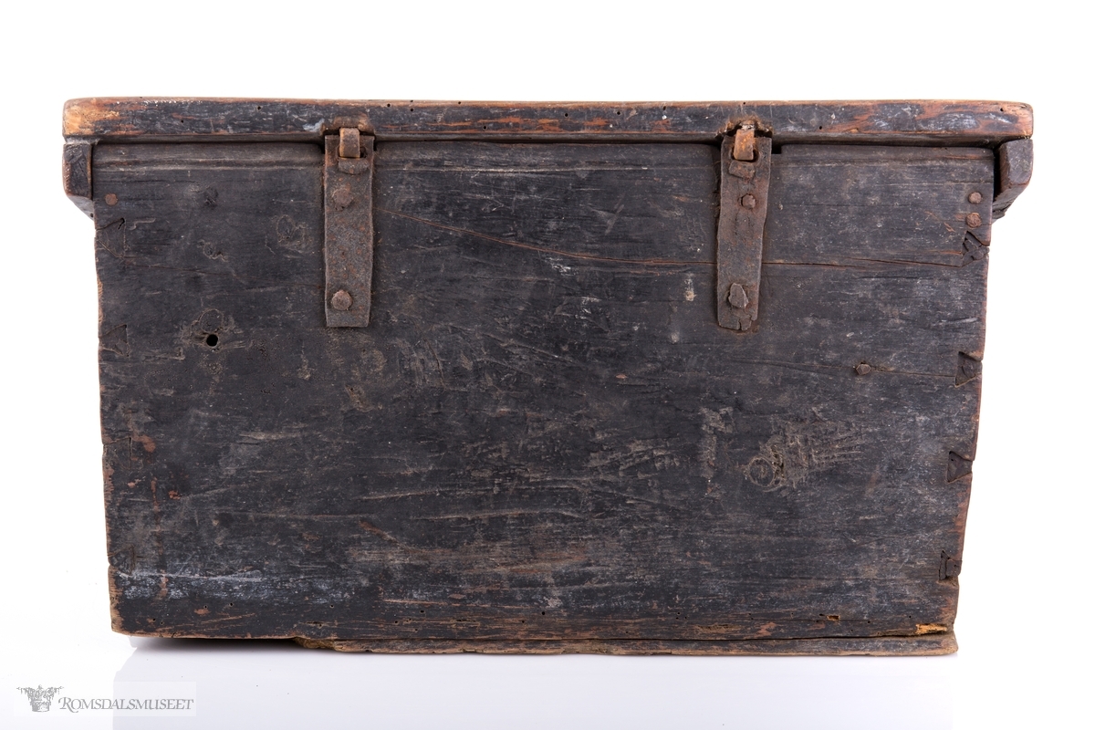 Rektangulær skrivekasse med skråstilt lokk, hengsler og låsbeslag. Bunnen er delvis dekket av et tykt lag med stivnet blekk med en trepinne i.