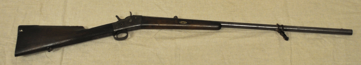 Enkelpipigt hagelgevär av system Remington. Huskvarna modell 12. kaliber: 20, slätborrad pipa. Tillverkningsnummer: 30365 från 1896. Tidig form av stopphane.