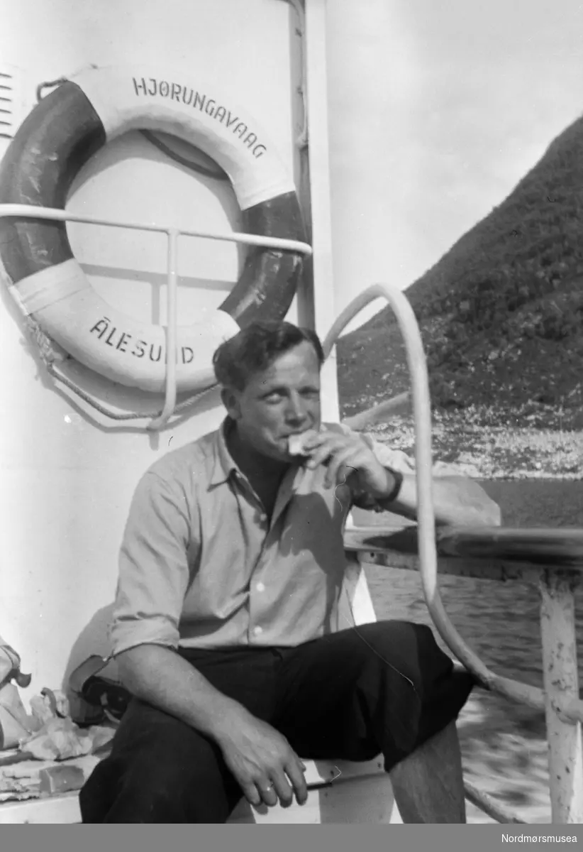 Mann spiser niste ombord på M/S Hjørungavaag av Ålesund. Bilferge? Livbøye. 1950-tall. Opplasta 17.11.2017. Fra familien Wågbø. Fra Nordmøre museums fotosamlinger.