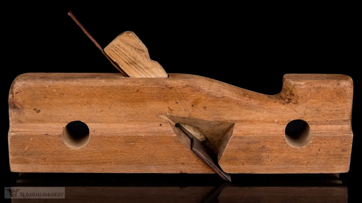 Smal rektangulær høvelstokk med tilskåret horn i forkant og avrundede hjørner. To gjennomgående opphengshull. Stokken er skåret slik at det er en støttekant ved siden av sålen. Gaffelformet høvelblad der et spor går langs sålen mellom de to tennene for høvling av fjær.